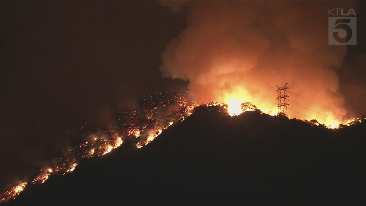 Sky5 is overhead of the northern flank of the Palisades Fire as it burns over the mountains, threatening San Fernando Valley communities.